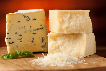 pieces of blue cheese and parmesan on a wooden cutting board bei