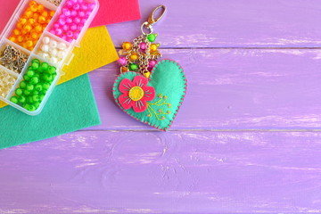Bright hand felt keychain, felt sheets, organizer with wooden beads on a lilac background with...