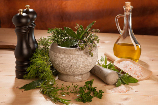 various spices on a wooden table with mortar, pestle and mills.