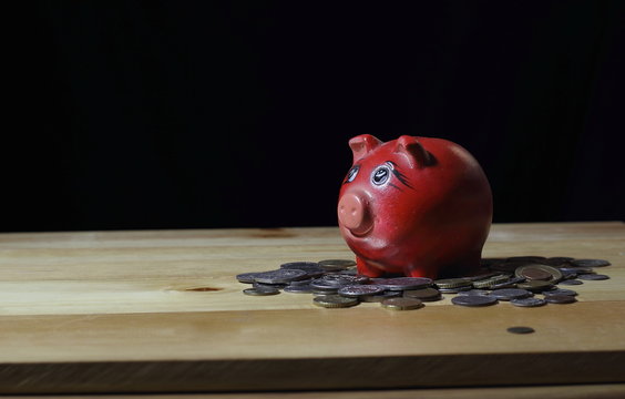 Piggy bank and coins on desk.