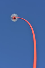 Iconic red wind wand kinetic sculpture on seafront promenade in New Plymouth.