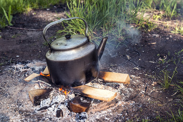 Kettle boiling on a fire outdoors.