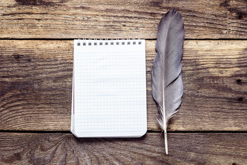 Background with empty notebook for text and gray feather on old