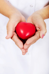 Elderly female doctor or nurse holding red toy heart