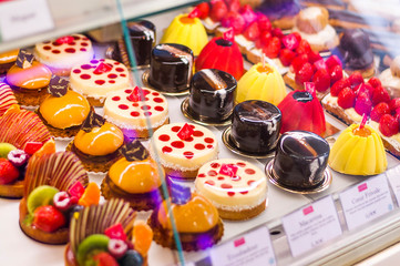 Pastry shop with variety of donuts, jelly beans, muffins, creme brulee, cakes with fruits and berries