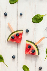 funny watermelon slices on sticks, spinach leaves and blueberries