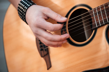 Male hands playing on guitar outdoors