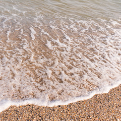 soft seawave with foam on sandy shore