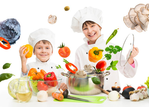 little chefs by table with flying vegetables in white uniform
