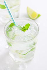 Non alcohol cold mojito cocktail with fresh lime, mint and crushed ice on a white plate, closeup