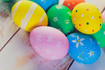 Easter eggs painted in pastel colors on white wooden background.
