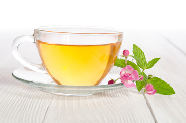 Glass cup of tea with mint and  rose on white wooden table
