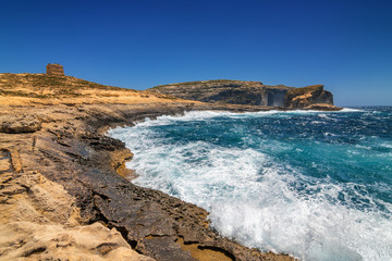 Surging waves break on the rocky shore of Dwejra bay in Gozo, Malta.