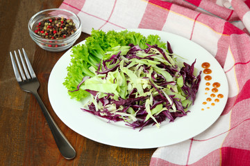 chopped cabbage in the dish by the piles of spices and Cutlery on the cloth on a wooden table