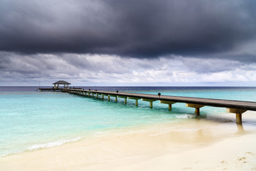 Obraz premium Wooden jetty over the beautiful Maldivian ocean with blue sky