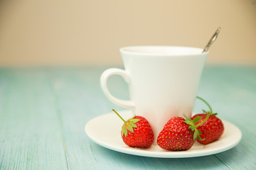 A cup with a drink and a strawberry on a blue