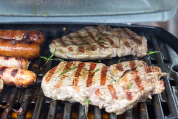 Grill grate with rib eye steaks and sausages