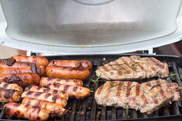 Grill grate with rib eye steaks and sausages