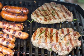 Grill grate with rib eye steaks and sausages
