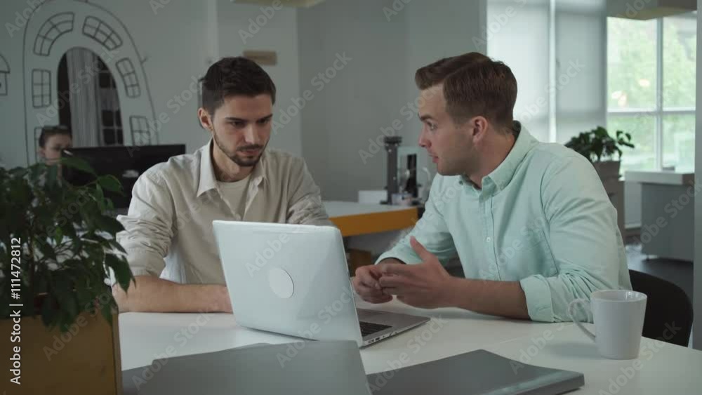 Aufkleber On the table computer flower in a pot folders with documents. Man works in modern open space room. Business team wearing in casual shirt with rolled up sleeves.