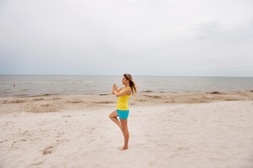 Fototapeta na wymiar Young woman making yoga exercises on the beach