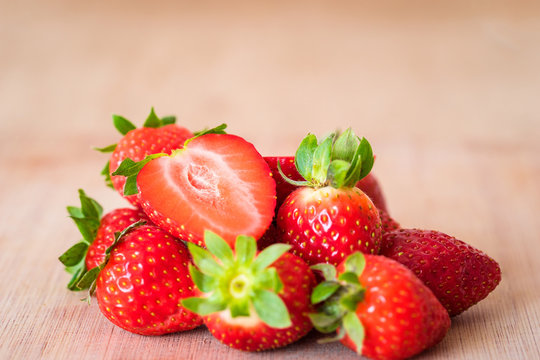 Pile of fresh strawberries on a wooden table. Close-up horizontal view.