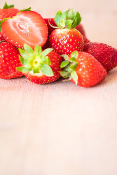 Pile of fresh strawberries on a wooden table. Detail vertical view.