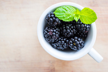 Top view of single cap filled with fresh blackberries and mint.