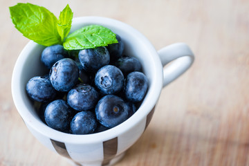 Blueberries in a small cap. Wooden table. Horizontal view.