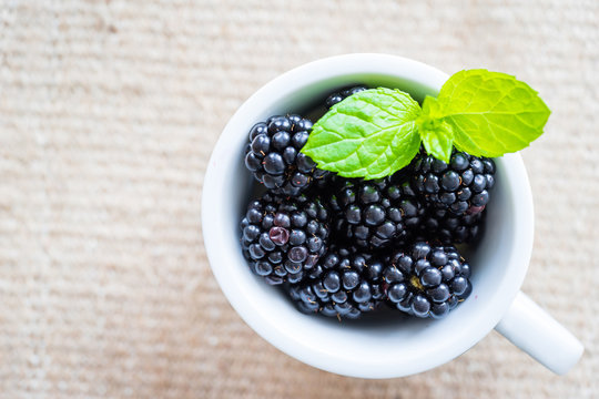 Top view of single cap filled with fresh blackberries and mint. Selective focus.