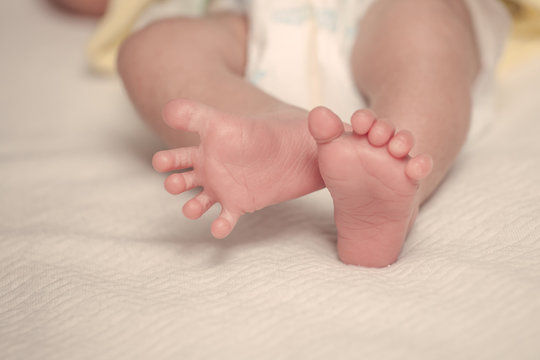 Newborn baby feet on bed in vintage color filter