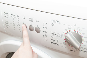 Close up of woman pushing button on washing machine