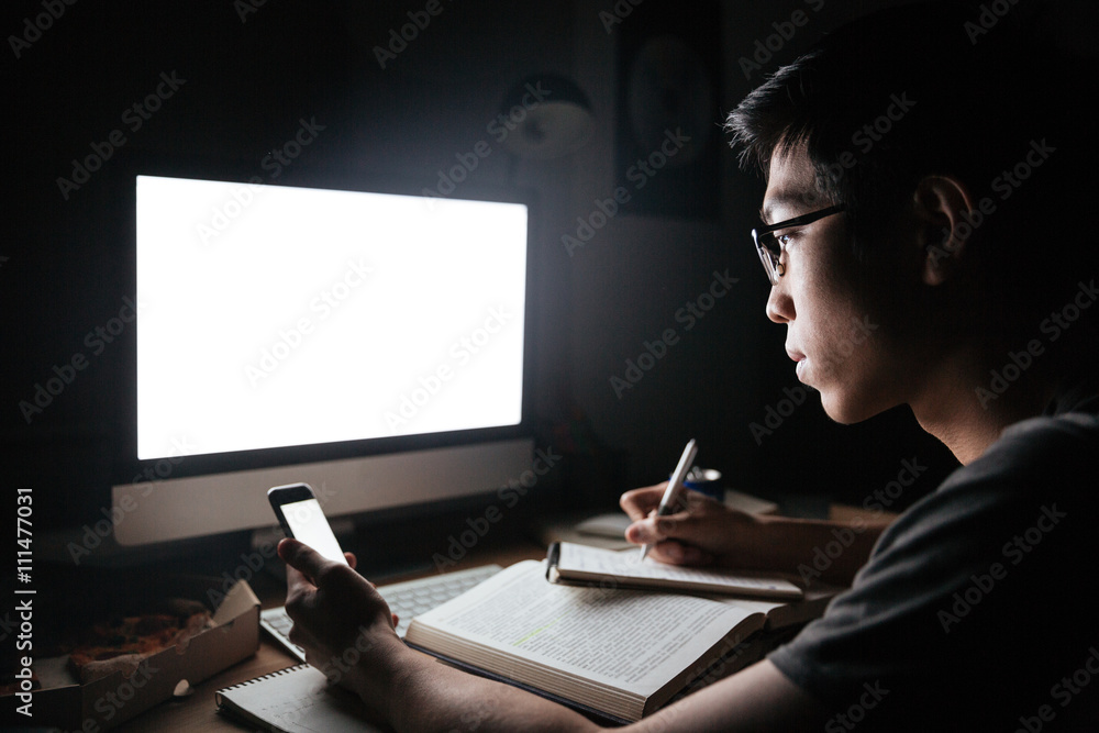 Wall mural focused asian man using blank screen mobile phone and computer