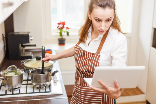 Young woman trying cooking with recipe from laptop