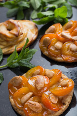 Tart with apricot and apple. Traditional french pie with fruits on dark marble background. Decorated almonds and mint leafs. Delicious dessert with copy space closeup.