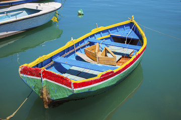 Fototapeta na wymiar Malta - Colorful Mediterranean traditional Luzzu fishing boat at Marsaxlokk on a sunny summer day with green sea