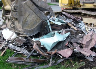 Close-up of excavator bucket loading metal parts from house demolition site