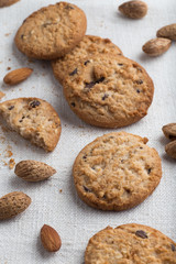 Cookies pile with chocolate chip and almond on light textile background. Delicious morning snacks for breakfast, brunch and lunch. Appetizing, healthy and fast food