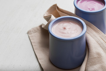 ogurts assortment  in ceramic bowls on wooden light background. Natural and fruit  healthy, diet, gourmet dessert for granola breakfast. Sweet yoghurts closeup.