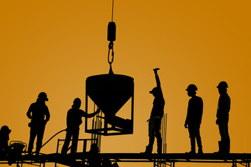 silhouette of construction worker team casting a concrete column by crane up lift bucket on scaffolding