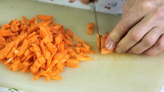 The cook cuts carrots on a chopping board