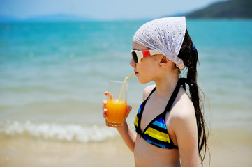 Kid girl with juice on the beach