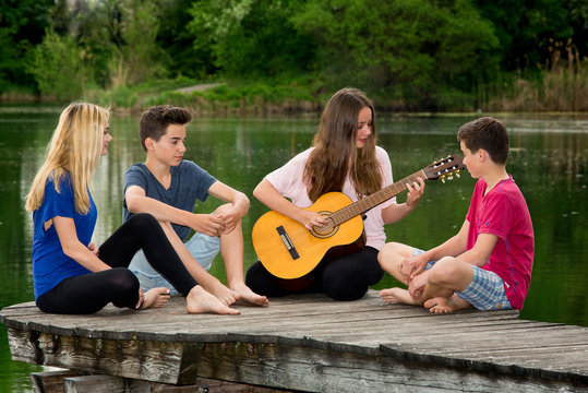Jugendliche musizieren daußen am See - Gitarre spielen