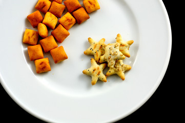 snack salati, in un piatto bianco su fondo nero, dall'alto