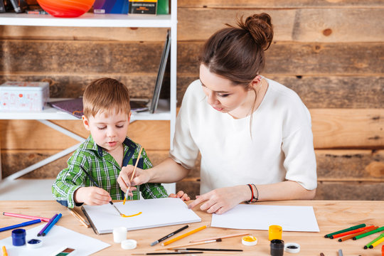 Mother and little son painting together in art school