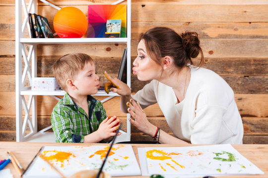 Mother touching face of son with hands painted in paints