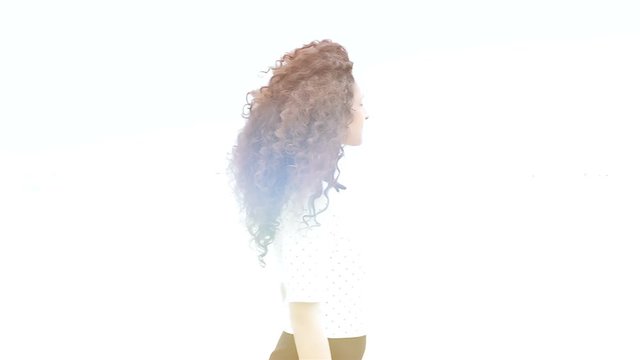 Romantic young woman with beautiful curly hair passing by the sea, slow motion