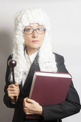 Female judge wearing a wig and Back mantle with eyeglasses holdi
