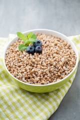 Buckwheat porridge in a bowl with mint leaves and blueberries.