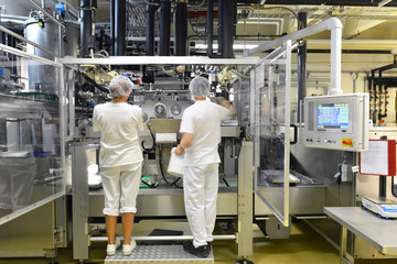 Arbeiter in der Lebensmittelproduktion an einer Maschine // workers in the food production on a...